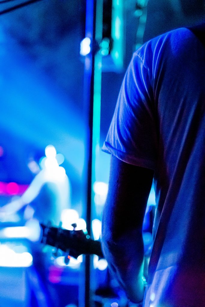 Guitarist captured in intimate nightclub setting, enveloped by vibrant blue lights.
